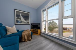 a living room with a blue couch and large windows at Chic 2-Bed Seafront Haven Near Felpham Beach in Felpham