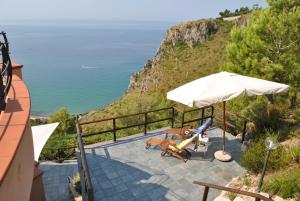 un patio con sombrilla, sillas y el océano en VILLA ROMANTIC COVE vista mozzafiato sul mare, en Latina