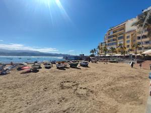 Ein Strand mit einem Haufen Stühle und Menschen darauf in der Unterkunft Luxury apartment Las Canteras in Las Palmas de Gran Canaria