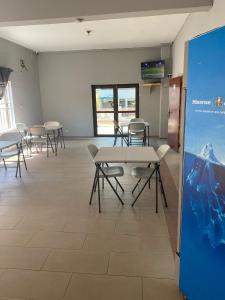 einen Konferenzraum mit Tischen, Stühlen und einem Bildschirm in der Unterkunft Estepona Playa Hostel in Accra