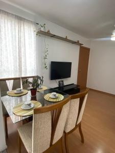 uma sala de jantar com uma mesa com cadeiras e uma televisão em Apartamento aconchegante em Betim em Betim