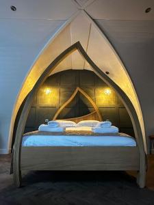 a bedroom with a bed with an arched head board at Badger at Owlet Hideaway - with Hot Tub, near York in Seaton Ross