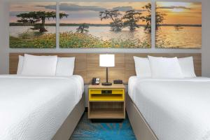 een kamer met twee bedden en een nachtkastje tussen twee bedden bij Days Inn & Suites by Wyndham Cabot in Cabot