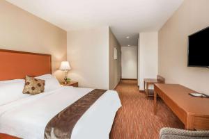 a hotel room with a large bed and a desk at Ramada by Wyndham Flushing Queens in Queens