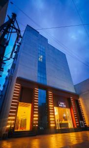 een groot glazen gebouw met lichten ervoor bij HOTEL EVERLAND in Rajkot