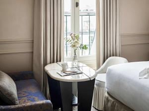 Cette chambre comprend une table, un lit et une fenêtre. dans l'établissement Sofitel Le Scribe Paris Opera, à Paris