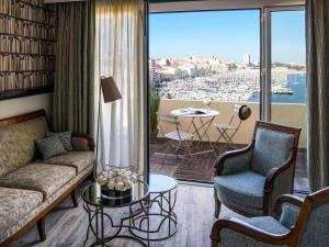 un soggiorno con divano e sedie e un balcone di Grand Hotel Beauvau Marseille Vieux Port - MGallery a Marsiglia