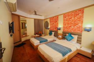 een hotelkamer met 2 bedden en een bakstenen muur bij HOTEL EVERLAND in Rajkot