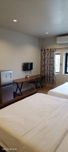 um quarto com uma cama e uma secretária com uma televisão em โรงแรมควีนส์ (Queen) em Ban Tha Kham