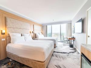 2 camas en una habitación de hotel con ventana grande en Novotel Sydney Brighton Beach en Sídney