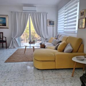 a living room with a yellow couch and a table at Ioanna D in Tolo