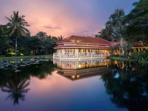 ein Gebäude auf einem See mit Lilien im Wasser in der Unterkunft Sofitel Angkor Phokeethra Golf & Spa Resort in Siem Reap