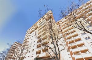 un edificio alto con un árbol delante de él en Apartamentos El Pilar Suites 3000 en Zaragoza