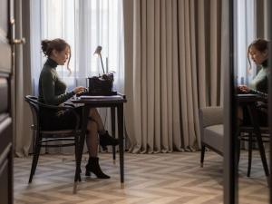 a woman sitting at a table in a hotel room at Hotel Century Old Town Prague - MGallery Hotel Collection in Prague