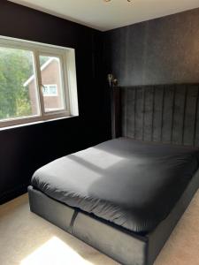 a bed in a black bedroom with a window at The hidden cottage in Wythenshawe