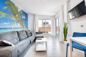 a living room with a gray couch and a palm tree mural at Sol Mogan Suites - Adults Only in Puerto de Mogán