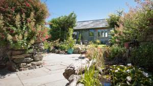 a garden in front of a house with flowers at Old Boswednack a rural retreat gem On the idyllic coast of Zennor to St Ives. Summer house garden parking for two cars and free WiFi. in Zennor