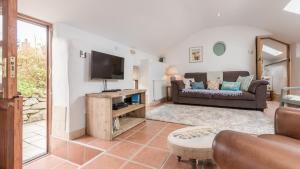 un soggiorno con divano e TV di Old Boswednack a rural retreat gem On the idyllic coast of Zennor to St Ives. Summer house garden parking for two cars and free WiFi. a Zennor