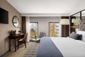 a hotel room with a bed and a desk and a window at Chekhoff Hotel Moscow Curio Collection By Hilton in Moscow