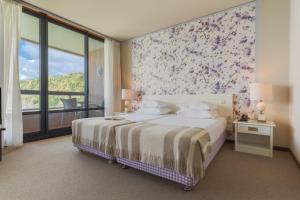 a bedroom with a bed and a large window at Pestana Bahia Praia Nature & Beach Resort in Vila Franca do Campo