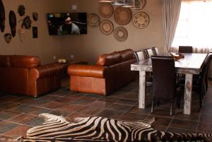 uma sala de estar com um sofá, uma mesa e um tapete de zebra em Casa de la Presa 3 em Polokwane