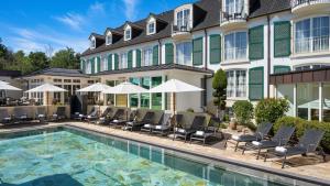 ein Hotel mit einem Pool mit Stühlen und Sonnenschirmen in der Unterkunft LIFESTYLE Resort Zum Kurfürsten in Bernkastel-Kues
