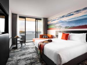 um quarto de hotel com uma cama grande e uma secretária em Novotel Devonport em Devonport