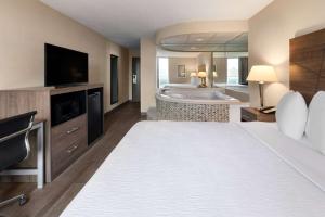 a hotel room with a large bed and a tub at Wingate by Wyndham Troy in Troy