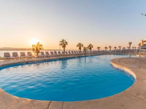 a swimming pool with chairs and the ocean in the background at DoubleTree by Hilton Malta in St Paul's Bay