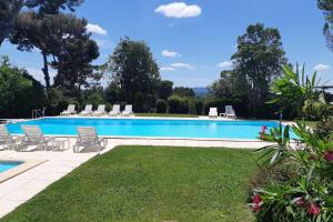 une grande piscine avec des chaises et une pelouse dans l'établissement Appartement Angelin - Welkeys, à Aix-en-Provence