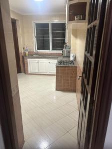 a kitchen with white cabinets and a tile floor at Appartement in Casablanca