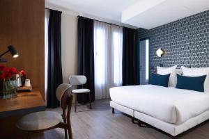 1 dormitorio con 1 cama blanca grande y almohadas azules en Bijou Hôtel Paris Boulogne, en Boulogne-Billancourt