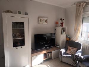 a living room with a large television and a chair at Habitacion centrica con baño privado in Portbou +1 photo