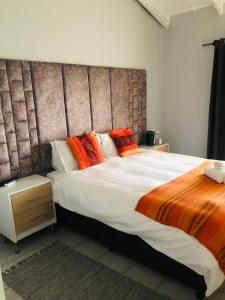 um quarto com uma cama grande com almofadas laranja e laranja em Elihle Guest house em Empangeni