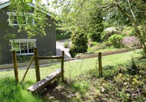 a fence in the grass next to a house at Sparrows Nest Holiday Cottage in Amroth