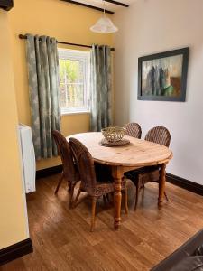 jadalnia z drewnianym stołem i krzesłami w obiekcie Sparrows Nest Holiday Cottage w mieście Amroth