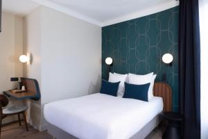 a bedroom with a white bed with a green wall at Bijou Hôtel Paris Boulogne in Boulogne-Billancourt