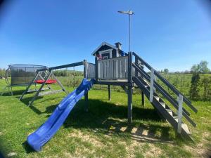 une aire de jeux avec un toboggan bleu dans un champ dans l'établissement Noclegi Beskidzkie Stodoły, à Odrzechowa