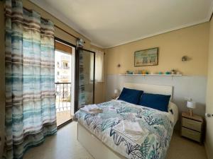 Un dormitorio con una cama con almohadas azules y una ventana en El retiro Denia, en Denia