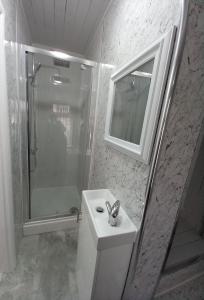 baño blanco con ducha y lavamanos en JosteeStay Apartments -Rooms en Goodmayes