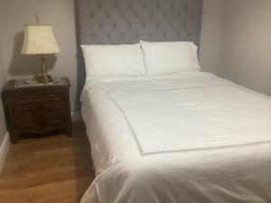 una cama con sábanas blancas y una lámpara en una mesita de noche en 4 Cois Glaisin View, en Kilcarn