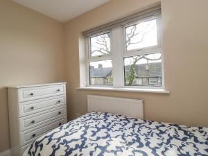 a bedroom with a bed and a dresser and a window at 5 Emmott Court in Colne