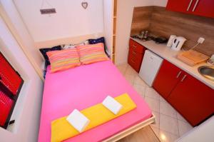 a small room with a pink bed in a kitchen at Majka 2 Apartments in Kotor