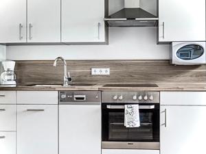 una cucina con armadi bianchi e forno in acciaio inossidabile di Alpen Appartements Oberlehengut - HIDEAWAY a Werfenweng