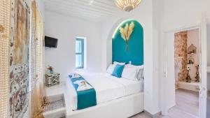 a white bedroom with a large bed with a blue headboard at Lady Stamatias House in Halki