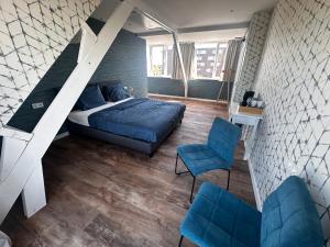 een slaapkamer met een bed en twee blauwe stoelen bij Eetcafé Punt in Roelofarendsveen