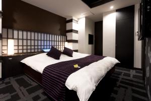 1 dormitorio con 1 cama grande con sábanas y almohadas a rayas en もしもしピエロ NEO 京都店, en Kioto