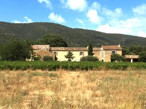 a house in a field with mountains in the background at La Rivayne in Lourmarin