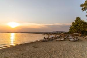 a beach with a bunch of chairs and a sunset at Ergon Beach House Nikiti in Nikiti