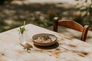 eine Schüssel Essen auf einem Holztisch mit einem Getränk in der Unterkunft Ergon Beach House Nikiti in Nikiti